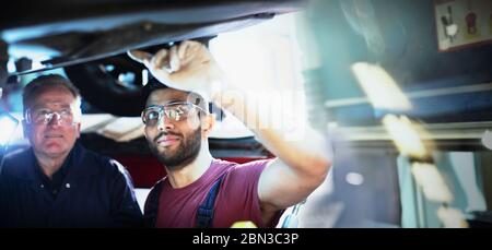 Männliche Mechaniker arbeiten unter dem Auto in der Autowerkstatt Stockfoto