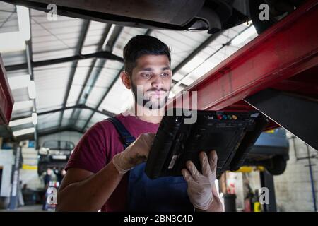Fokussierte männliche Mechaniker mit Diagnosegeräten in der Autowerkstatt Stockfoto
