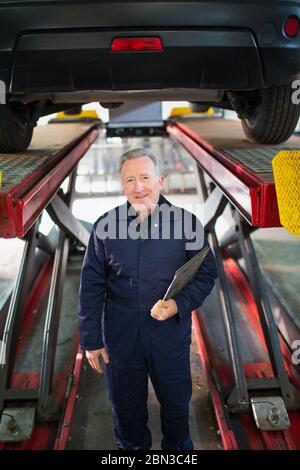 Portrait zuversichtlich, männlichen Mechaniker unter dem Auto in der Kfz-Werkstatt Stockfoto