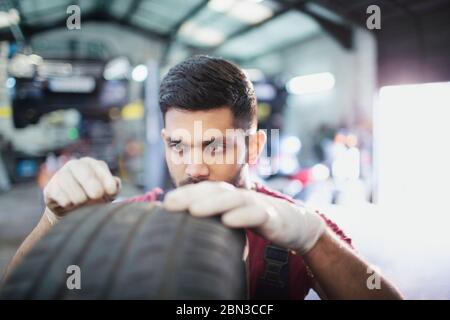 Fokussierte männliche Mechaniker Prüfung Reifen in der Auto-Werkstatt Stockfoto