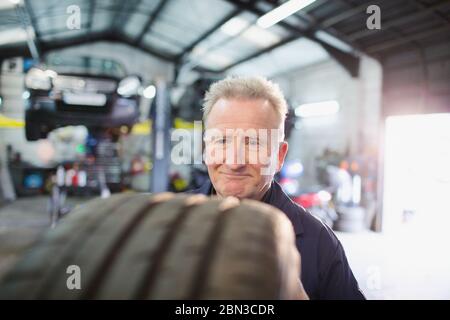 Männlicher Mechaniker, der Reifen in der Autowerkstatt untersucht Stockfoto