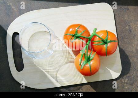 Tomatensaft unter frischen Tomaten auf der obersten Ansicht Küche Holzbrett. Stockfoto