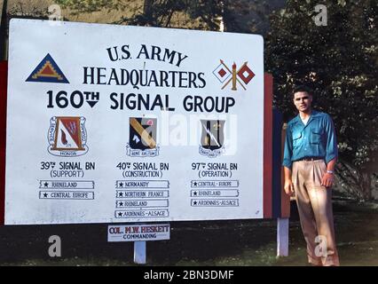 Ein US-Soldat, der Mitte der 1950er Jahre in Deutschland stationiert war – ein Mitglied der 160. Signalgruppe ist neben dem Eingangsschild der Einheit auf dem Bild der Zentrale der Panzer Kaserne (PK) in Böblingen abgebildet. Das Abzeichen der 7. Armee ist oben links, die 160ste Signalgruppe oben rechts und die Abzeichen ihrer drei Bataillone sind ebenfalls zu sehen. Ab 1955 war die 160ste Signal Group in der Nachkriegszeit unter der 7. US-Armee deutschlandweit in der Panzerkaserne (PK) in Böblingen (Böblingen) bei Stuttgart tätig. Oberst Marcus W Heskett war der Kommandant. Stockfoto