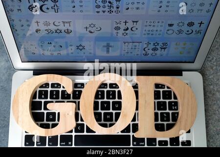 Holzbuchstaben bilden das Wort Gott auf Laptop. Interreligiöser und interreligiöser Dialog. Stockfoto