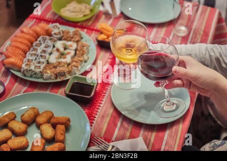 Zwei Personen jubeln bei einem Abendessen mit Sushi und gebratenem Käse Stockfoto