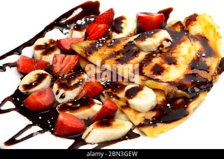 Pfannkuchen mit Erdbeere, Banane und Schokoladensirup auf weißem Hintergrund Stockfoto