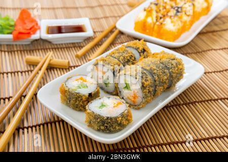 Gebackene Sushi-Brötchen aus nächster Nähe. Unagi und fliegende Fische ROE, Futomaki ASI. Gericht mit japanischer Küche Stockfoto