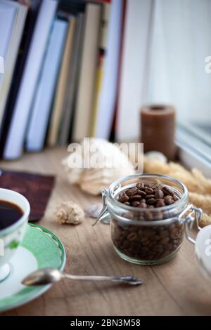 Kaffeesorten, die aus einer Dose auf einem hölzernen Hintergrund gegossen werden. Kaffeemodebung. Kaffeebohne Dunkler Hintergrund mit Platz für Text. Küchentisch. Stockfoto