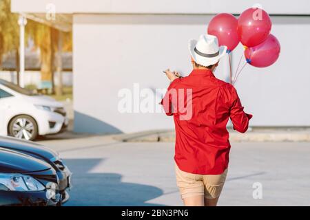 Rückansicht des homosexuellen Mann im roten Hemd mit roten Ballons vom Parkplatz der Partei am Nachmittag zu verbinden. Stockfoto