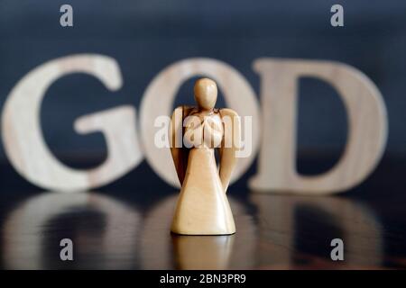 Holzbuchstaben bilden das Wort GOTT und Engel. Christliches Symbol. Stockfoto