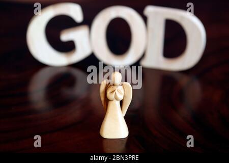 Holzbuchstaben bilden das Wort GOTT und Engel. Christliches Symbol. Stockfoto