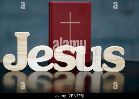 Holzbuchstaben bilden das Wort JESUS und die Bibel. Christliches Symbol. Stockfoto