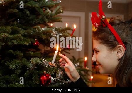 Mädchen, das auf eine Kerze auf Weihnachtsbaum schaut. Genf. Schweiz. Stockfoto