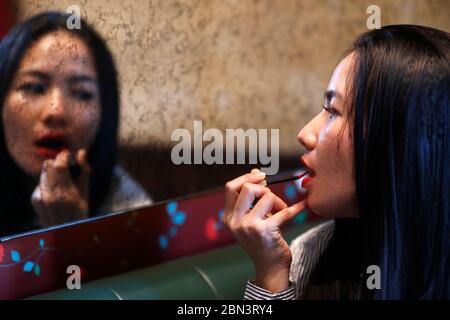 Frau, die Lippenstift anwendet. Ho Chi Minh Stadt. Vietnam. Stockfoto