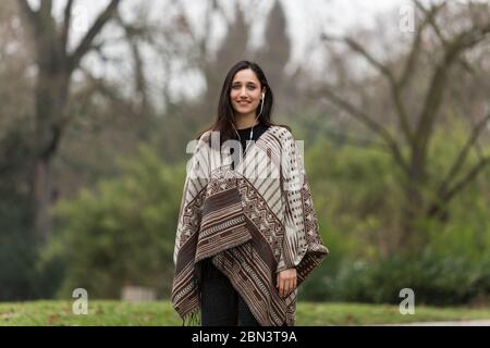 Junge Frau lächelnd in modischen Poncho im Park gekleidet. Stockfoto