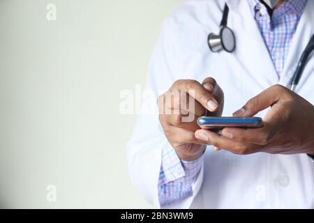 Der männliche Arzt im weißen Mantel verwendet ein modernes Smartphone-Gerät Stockfoto
