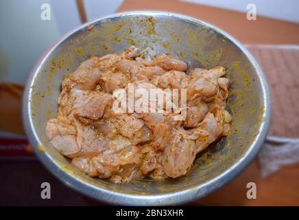 Frisch gewürzte Hähnchenflügel in einer Metallschüssel zubereitet, bereit zum Kochen und als schmackhaftes und gesundes Gericht genossen werden, Gewürze auf rohem Hähnchenfleisch werden Stockfoto