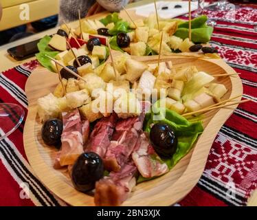 Eine rustikale Platte mit Aufschnitt: Schinken, Käse, Oliven und andere traditionelle Fingerfood, eine gemeinsame rumänische Vorspeise auf einem Holzteller serviert Stockfoto