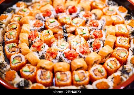 Eine Auswahl an Sushi, das auf einem runden schwarzen Gericht liegt Stockfoto