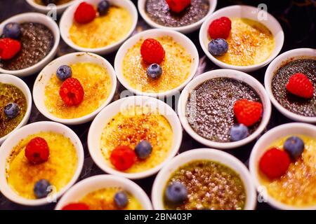 Zwei Sorten Soufflé in weißen Schalen, dekoriert mit Himbeeren und Heidelbeeren Stockfoto