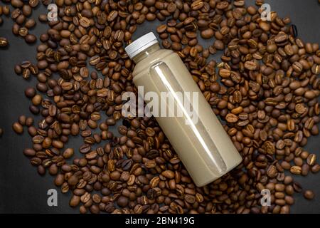 Abgefüllter Milchkaffee wird auf geröstete Kaffeebohnen gelegt. Stockfoto
