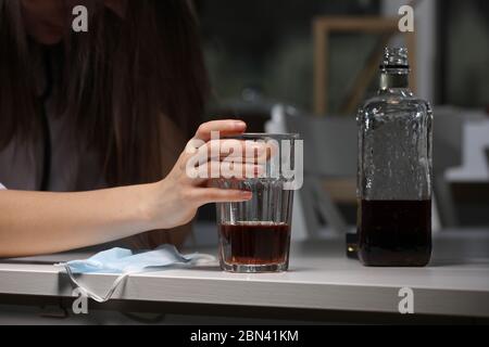 Trink Problem Alkoholismus während Coronavirus Isolation Quarantäne Zeitkonzept. Frau hält Glas mit Alkohol trinken. Gesichtsmaske auf Hintergrund Stockfoto