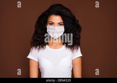 Porträt von charmanten schönen Afro american Mädchen gut aussehen genießen Emotionen tragen Casual style Outfit Gesichtsschutz Grippe Maske isoliert braune Farbe Stockfoto