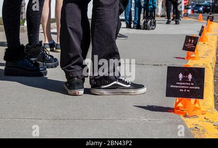 Mai 2020 Montreal, Qc, Can. Kunden warten in der Schlange draußen neben 2m sozialen distanzierenden Französisch Mini-Kegel Marker Coronavirus COVID-19 Pandemie Stockfoto