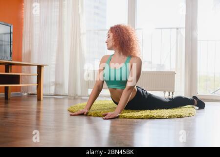 Mädchen machen Sport-Übungen, Training, Gymnastik, tun Liegestütze, zu Hause Teppich strecken während der Welt covid Lockdown Stockfoto