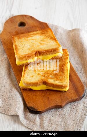 Hausgemachtes Gegrilltes Käse-Sandwich auf einem rustikalen Holzbrett auf weißem Holzhintergrund, Seitenansicht. Stockfoto