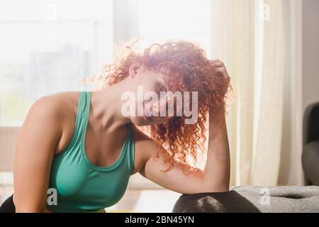 Gesicht des Mädchens mit roten Haaren tragen Sport grün Top-BH. Fenster mit weichem Morgenlicht. Stockfoto