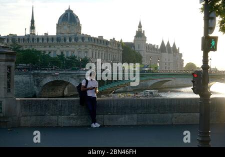 Ein Mann, der sein Handy mit der Brücke Pont d'Arcole über die seine betrachtet, im Hintergrund Greffe du Tribunal de Commerce de Paris und Conciergerie.Paris.Frankreich Stockfoto