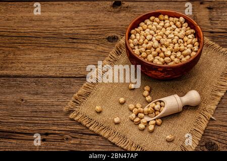 Trockene Kichererbsen in Keramik Schüssel auf alten Holzbrettern Hintergrund. Traditionelle Zutat zum Kochen Hummus. Nahöstliche und mediterrane Küche Stockfoto