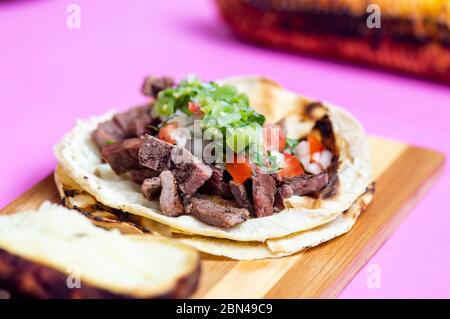 Mexikanische Carne Asada Tacos, buchstäblich gegrilltes Fleisch Tacos. Es handelt sich um gehacktes gegrilltes Rindfleisch, das auf weichen Maiskolben mit Salsa verde und Pico de ga serviert wird Stockfoto