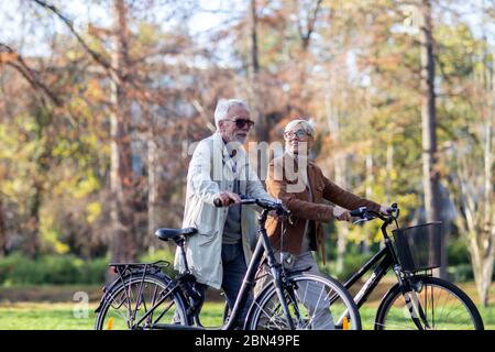 Altes Paar mit Fahrrädern, die im Park spazieren gehen Stockfoto