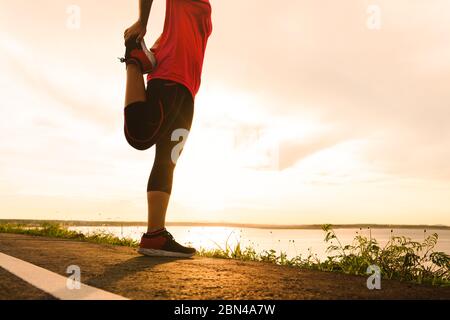 Frau Stretching Beinmuskulatur Vorbereitung für Sonnenuntergang Trail Run Stockfoto