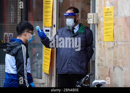 London, Großbritannien. 12 Mai 2020. Ein Wachmann überprüft die Temperatur eines Kunden in einem Supermarkt in Chinatown während der laufenden Sperrung der Coronavirus-Pandemie. Normalerweise sind die Straßen mit Touristen und Besuchern überfüllt, aber als Folge von Covid 19, wird der Fußabfall deutlich reduziert. Kredit: Stephen Chung / Alamy Live News Stockfoto