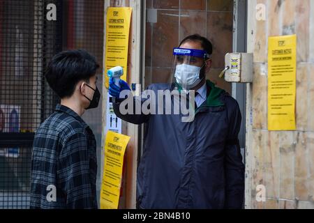 London, Großbritannien. 12 Mai 2020. Ein Wachmann überprüft die Temperatur eines Kunden in einem Supermarkt in Chinatown während der laufenden Sperrung der Coronavirus-Pandemie. Normalerweise sind die Straßen mit Touristen und Besuchern überfüllt, aber als Folge von Covid 19, wird der Fußabfall deutlich reduziert. Kredit: Stephen Chung / Alamy Live News Stockfoto