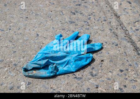 Gebrauchte medizinischen blauen Handschuh auf dem Boden während Coronavirus COVID-19 Pandemic, Nahaufnahme Stockfoto