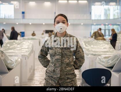 Airman 1st Class Arielle Robles, Verwaltungsexpertin der 103rd Maintenance Group, hilft bei der Einrichtung von Betten in einem Recovery Center in der Kaiser Hall an der Central Connecticut State University in New Britain, Connecticut, 21. April 2020. Robles ist eine Studentin der Bewegungswissenschaft an der Universität und hilft nun, ihr übliches Klassenzimmer in Überspannungsraum für lokale Krankenhäuser umzuwandeln, als Reaktion auf die COVID-19-Pandemie. (USA Foto der Air National Guard von Staff Sgt. Steven Tucker) Stockfoto