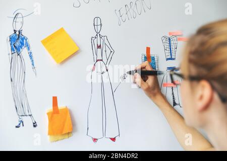 Modedesignerin skizziert neue Bekleidungskollektion auf Whiteboard Stockfoto