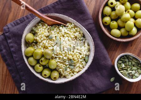 Bulgur mit grünen Oliven und Pepitas, gesunde Ernährung einfach Rezept aus lange gelagerten Lebensmitteln. Stockfoto