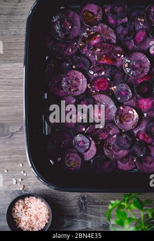 Scheiben lila Karotte mit rosa Salz und Olivenöl zum Rösten. Stockfoto