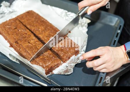 Frau schneidet Brownie in Stücke. Stockfoto