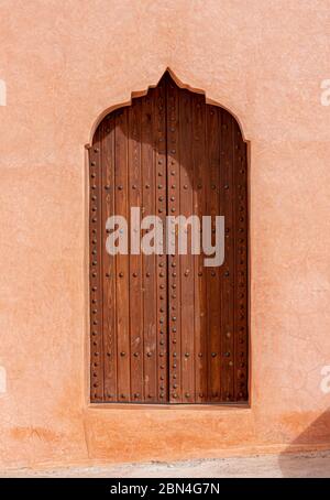 Traditionelle arabische Architektur, holztür im muslimischen Stil und rote Lehmwand Stockfoto