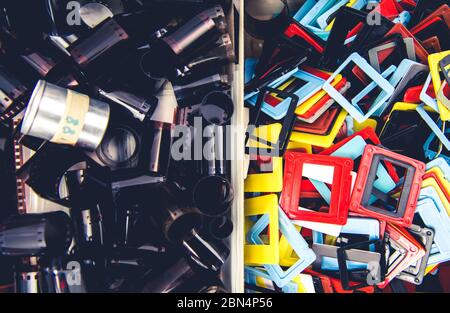 Zwei größere Behälter mit 35mm Negativfilm-Rollen Silberbehälter und bunten Kunststoff-Dia-Halterungen gefüllt. Stockfoto