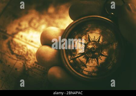 Nahaufnahme Der Kaukasischen Männlichen Hand Hält Goldenen Kompass Und Karte Auf Dem Tisch. Stockfoto