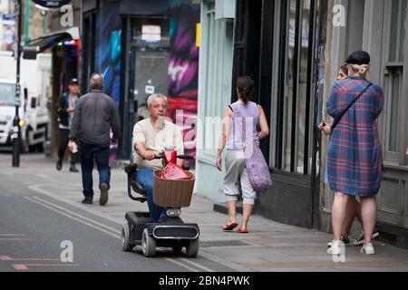 LONDON, Großbritannien - 17. September 2019: Ein Mann fährt auf einem Roller für ältere Menschen in Bricklane Shopping Stockfoto