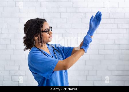 Afroamerikanische Veterinärmedizinerin, die Schutzhandschuhe in der Tierklinik anlegt Stockfoto