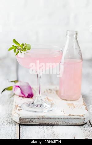 Sommer Erfrischungsgetränke. Light Pink rose Cocktail, mit Rose Wein auf einem weißen Tisch. Mit rosa Blüten. Platz kopieren Stockfoto